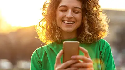 The Paperless Brokerage A woman standing outside while smiling at her phone