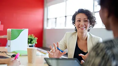 Enrichment Quote Woman dressed in business casual attire sitting with colleagues smiling.