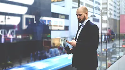 Relay Man using his phone and holding a disposable coffee mug.