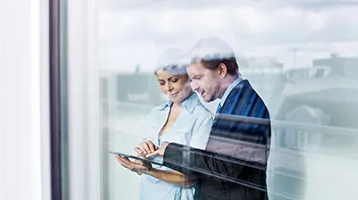 Translations Colleagues dressed in business attire interacting with a tablet.