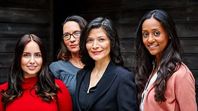 M&A Activity, Serendipity and Synchronicity – One Woman’s Tale of Turning Heartbreak into Heroism Four women dressed in business attire standing next to each other while slightly smiling