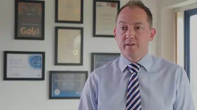 Ravenhall Risk Solutions - eTrading A man in a tie standing in front of a number of awards