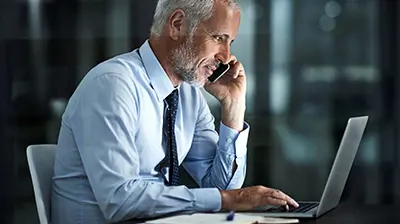 7 Steps to Digital Transformation: A Roadmap for Independent Insurance Agencies A man working on a laptop computer while on a phone call