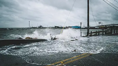 Are You Risking the Life of Your Business to a Disaster? Waves crashing over a fence onto a road