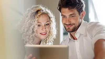 The 5 Benefits of Being a Digital Agency Man and woman in casual attire looking down at a tablet in the woman's hand.