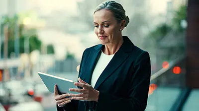 Insight Disparate Systems Woman in business attire standing outside using a tablet.