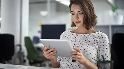 Insight Insurer Connectivity Woman in business casual attire sitting at desk using a tablet.