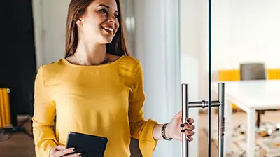 Our Innovation True North A woman smiling while opening a glass door