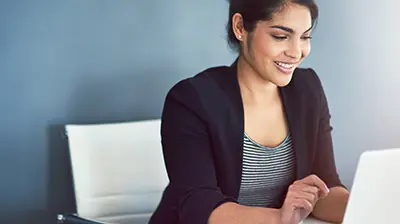 Connect Your Sales and Marketing Teams with Applied Epic for Salesforce A woman smiling while using her laptop