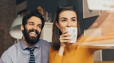 Understanding Millennial & Gen Z Insurance Buying Behaviors a young man and woman taking a selfie in an office, the woman is holding a coffee cup in front of her face.
