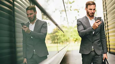 Applied MobileInsured A man in a suit standing outside while using his phone